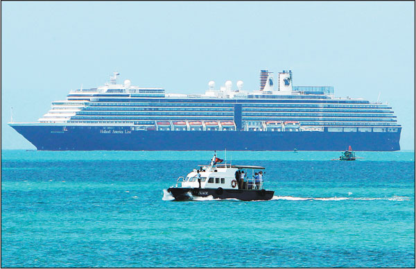A boat (foreground) carries samples from passengers aboard the cruise ship Westerdam (background) off Sihanoukville, Cambodia, on Thursday. The cruise ship, which has 1,455 passengers and 802 crew members and has been turned away by four governments due to fears amid the coronavirus outbreak, anchored off Cambodia on Thursday for health checks.Heng Sinith/Ap