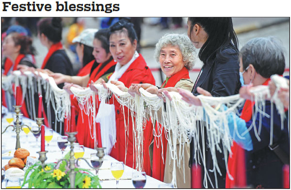 Seniors hold noodles, a symbol of longevity, at a banquet in Chongqing's Fuling district on Sunday to mark Chongyang Festival. Also known as the Double Ninth Festival (the ninth day of the ninth month on the Chinese lunar calendar), the festival is an occasion to care for and send blessings to seniors across China. Chen Chao / China News Service