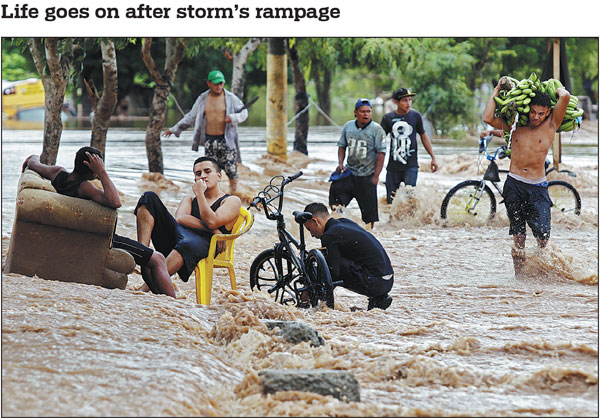 Men sit casually as others wade across a flooded street in the Honduran city of El Progreso on Wednesday after Hurricane Iota, now downgraded to a tropical storm, had passed. Iota killed at least 10 people during its destructive advance across Central America.Str/afp