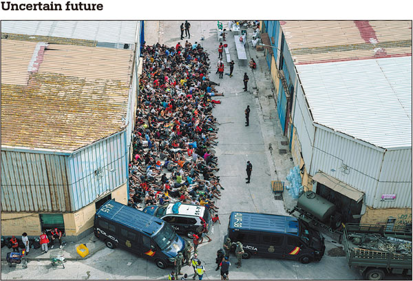 Unaccompanied minors who crossed into the Spanish enclave of Ceuta in North Africa are gathered on Wednesday outside a warehouse used as a temporary shelter as they wait to be tested for COVID-19. The port city of Ceuta lies next to Morocco but falls under Spanish sovereignty. Thousands of migrants, who have become pawns in a diplomatic spat between Morocco and Spain, awoke to an uncertain future on Wednesday, after sleeping wherever they could find shelter following their massive border breach into the Spanish enclave. BERNAT ARMANGUE/AP