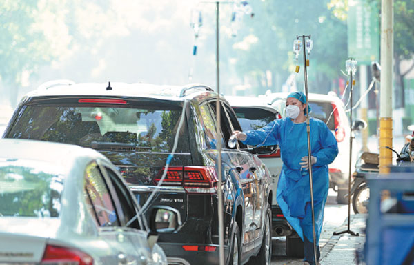 Patients in their cars are given intravenous drips to treat fever at a clinic in Ruili, Yunnan province, on Saturday. Cities nationwide are bracing for peaks of COVID-19 infections by adding critical-care beds and expanding the capacity of fever clinics.China Daily