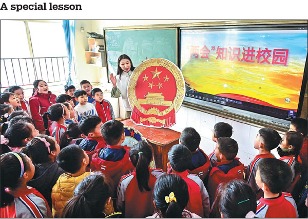 Displaying the national emblem of China, a teacher imparts knowledge about the two sessions to students at Qingzhou Economic Development Zone Primary School in Weifang, Shandong province, on Wednesday. The two sessions are the annual meetings of the National People's Congress, the country's top legislative body, and the National Committee of the Chinese People's Political Consultative Conference, the country's top political advisory body, which open respectively on Sunday and Saturday this year.Wang Jilin/for China Daily