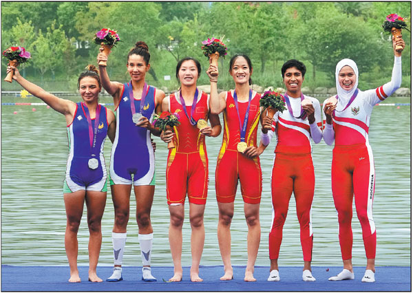 Winners of the women's lightweight double sculls rowing event pose for a group photo on Sunday during the awards ceremony at the 19th Asian Games in Hangzhou, Zhejiang province. Chinese duo Zou Jiaqi (third from left) and Qiu Xiuping (third from right) clinched the first gold medal of the Games with a time of 7 minutes and 6.78 seconds in the final race in this rowing category. The teams from Uzbekistan and Indonesia won silver and bronze, respectively.      Wei Xiaohao / China Daily