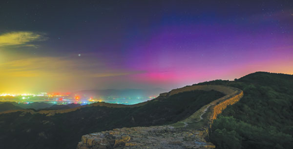 The aurora borealis, also known as the northern lights, glow on the horizon on Saturday evening at the Simatai section of the Great Wall in Beijing's Yanqing district. An unusually strong solar storm hitting Earth produced the stunning displays of color in the skies across the Northern Hemisphere, including in the Chinese capital, which is on a low geomagnetic latitude.Zheng Zhi/For China Daily