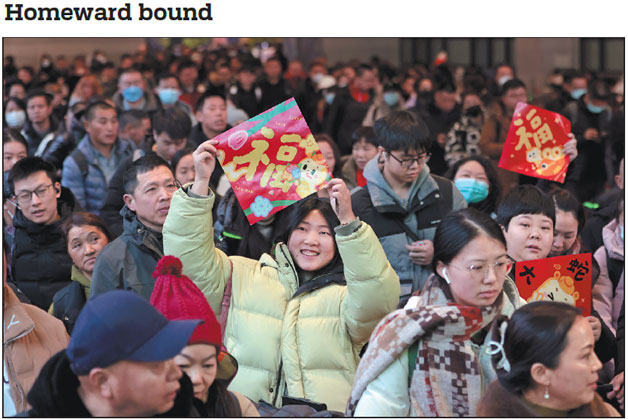 Passengers, some of whom are displaying the Chinese character fu, which means happiness and luck, wait in line to board trains at Beijing West Railway Station on Tuesday, the first day of China's 40-day Spring Festival travel rush. Nine billion interregional trips are expected during this year's travel rush.       Zou Hong / China Daily