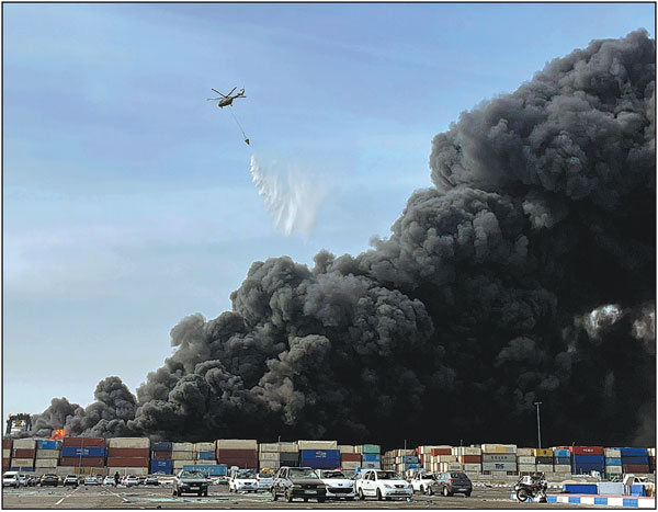 A helicopter drops water to douse a raging fire that started after a massive explosion rocked a port near the southern city of Bandar Abbas, Iran, on Saturday.Razieh Pudat/Isna/Ap
