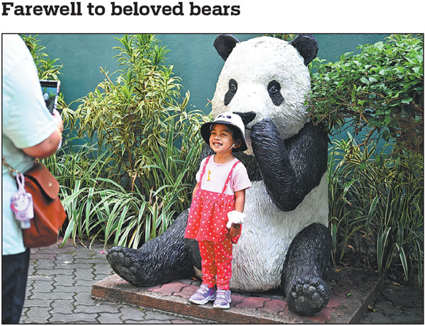 A girl poses for a photo with a giant panda sculpture at Zoo Negara near Kuala Lumpur, Malaysia, on Saturday. Giant panda pair Xing Xing and Liang Liang returned to China on Sunday after their 11-year stay in the Southeast Asian country.Cheng Yiheng/Xinhua