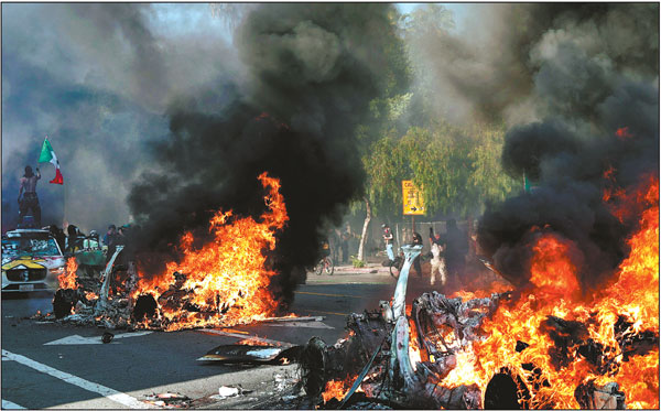 A protester holds up a Mexican flag as burning cars line a street on Sunday in Los Angeles, the United States. Thousands protested against the ongoing crackdown on immigrants, blocking a major freeway and setting self-driving vehicles on fire as law enforcement used tear gas, rubber bullets and flash-bang grenades to control the mob.Mario Tama/Getty Images/Afp