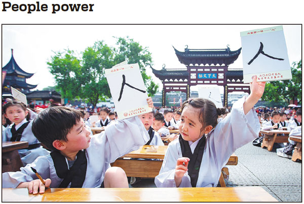 First-graders display the Chinese character for ren, or people, during a ceremony on Monday to mark the start of the new semester at the Confucius Temple, in Nanjing, Jiangsu province. The ceremony was held to teach students about traditional Chinese culture. Su Yang / For China Daily