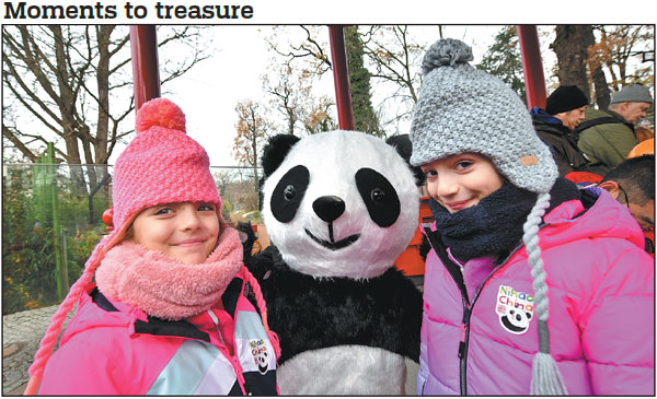 Children pose for a photo with a person in a panda costume at the Berlin Zoo in Germany on Friday. The zoo held a farewell ceremony for four-year-old panda twins Paule and Pit, who will move to China in mid-December. The twins were the first giant pandas born in Germany.    Ren Pengfei / Xinhua