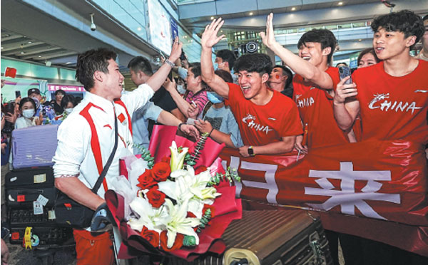 Diver Wang Zongyuan (left), who won gold with teammate Long Daoyi in the men's synchronized 3-meter springboard event and silver in the men's individual 3m springboard at the Paris Olympics, greets well-wishers on Monday at Beijing Capital International Airport.China Daily