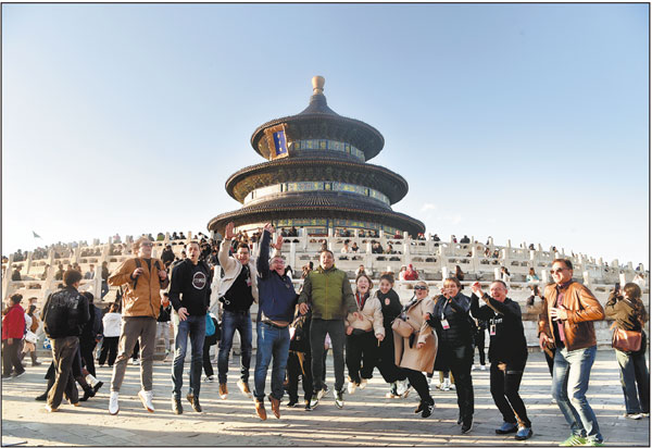 Foreign tourists cheer during a visit to the Temple of Heaven in Beijing on Nov 3. In the first 11 months, China received 17.45 million visa-free entries made by foreign visitors, accounting for about 60 percent of all foreign entries. Provided to China Daily